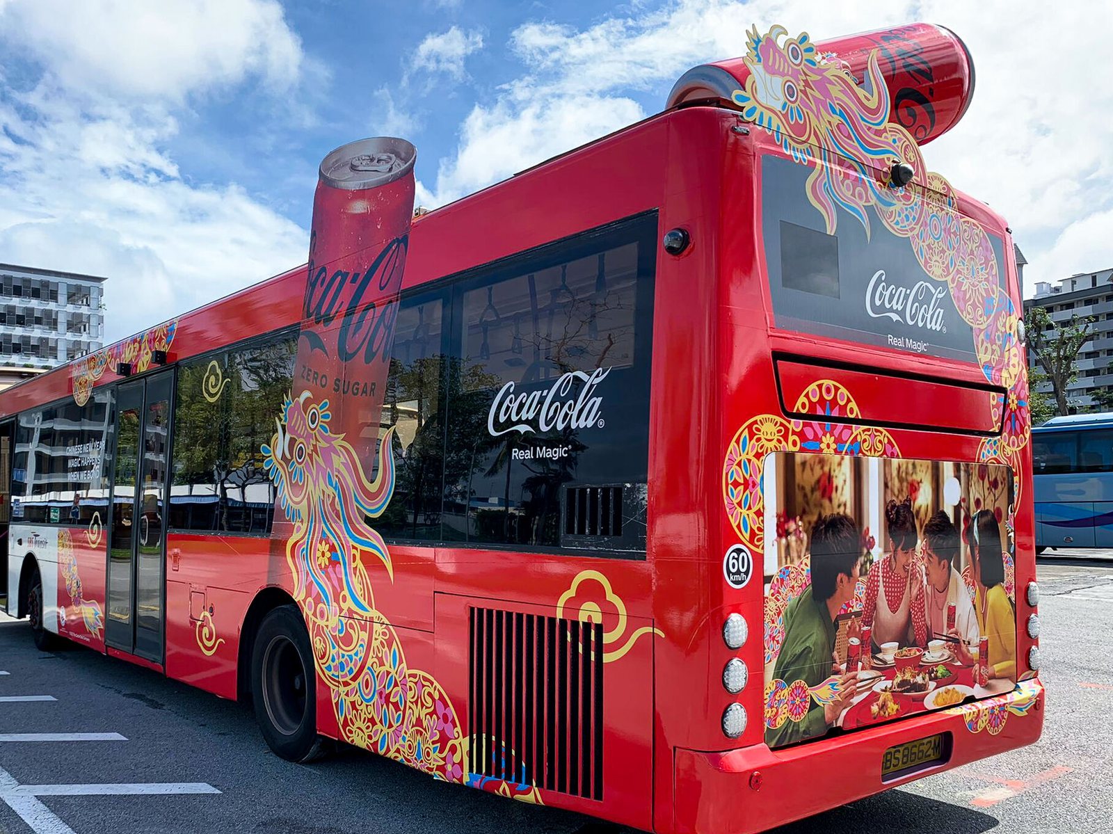 Coca-Cola Chinese New Year bus transit wrap, rear three-quarter view of an SBS Transit bus with a die-cut dragon can on the roofline