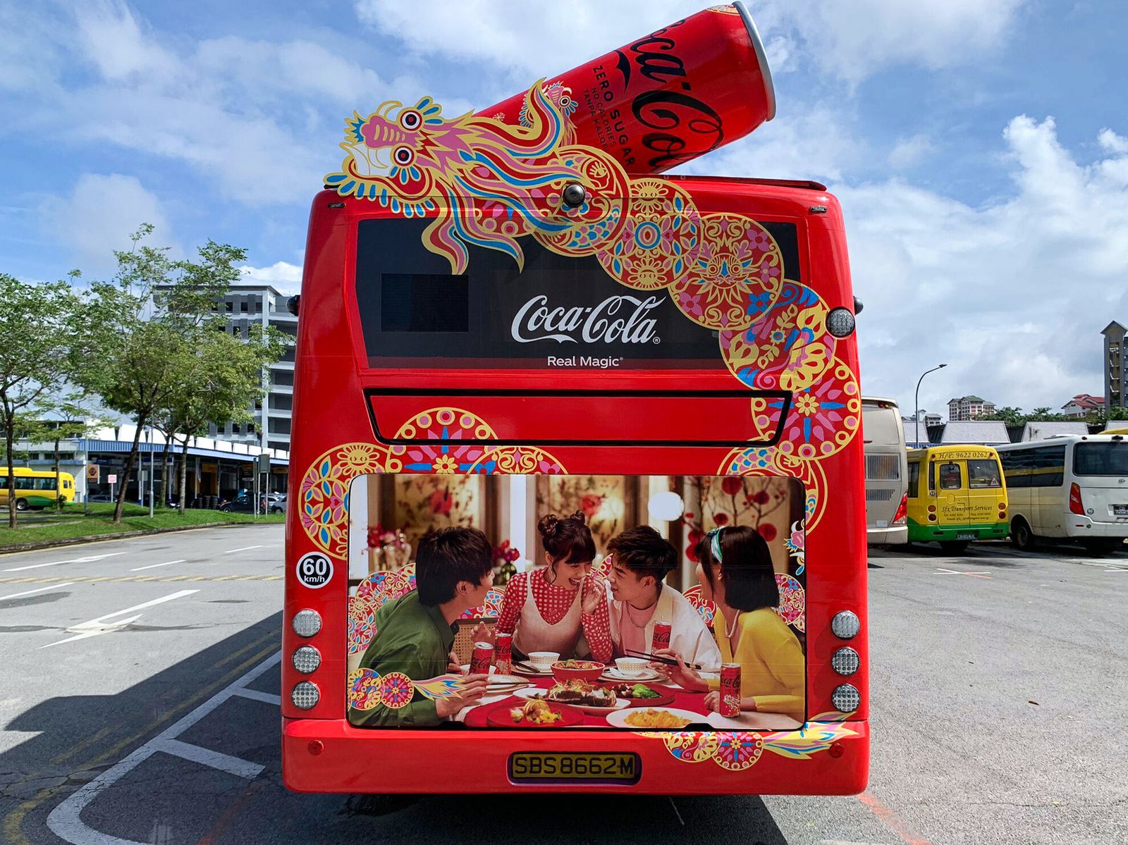 Coca-Cola Chinese New Year bus transit wrap, straight-on rear view showing the dragon motif and a lifestyle ad panel in the rear window
