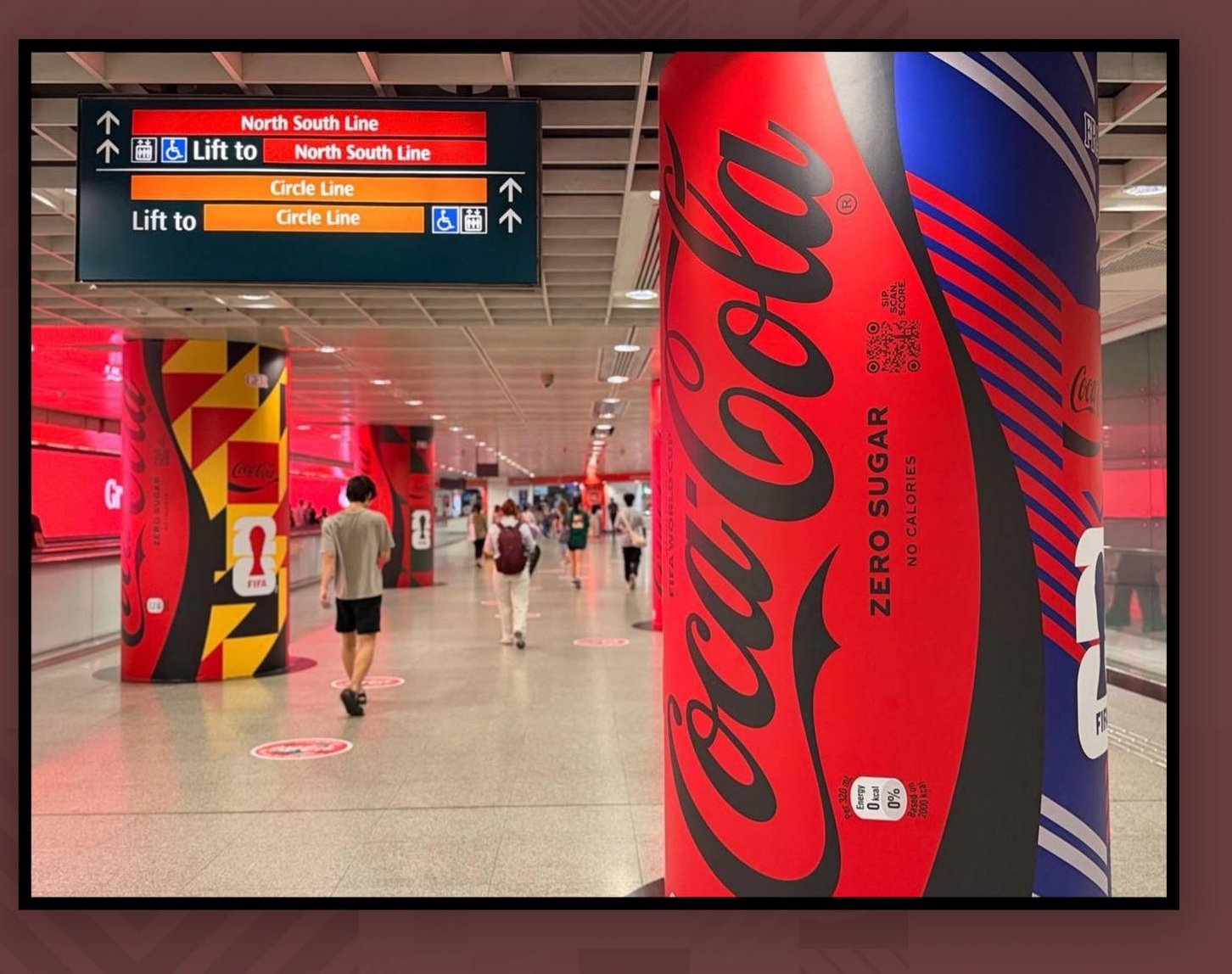 Coca-Cola FIFA World Cup pillar wrap installed at a Singapore MRT station, commuters walking past